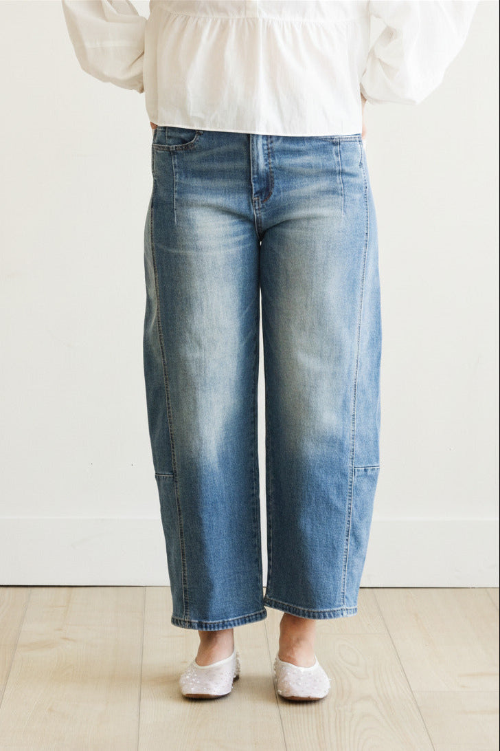 Person wearing blue jeans and a white top on a plain background