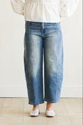 Person wearing blue jeans and a white top on a plain background