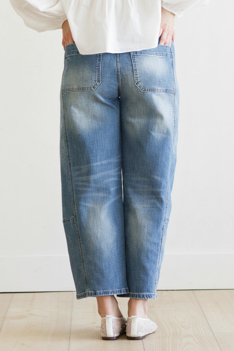 Person wearing blue jeans and a white shirt on a plain background