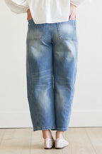 Person wearing blue jeans and a white shirt on a plain background