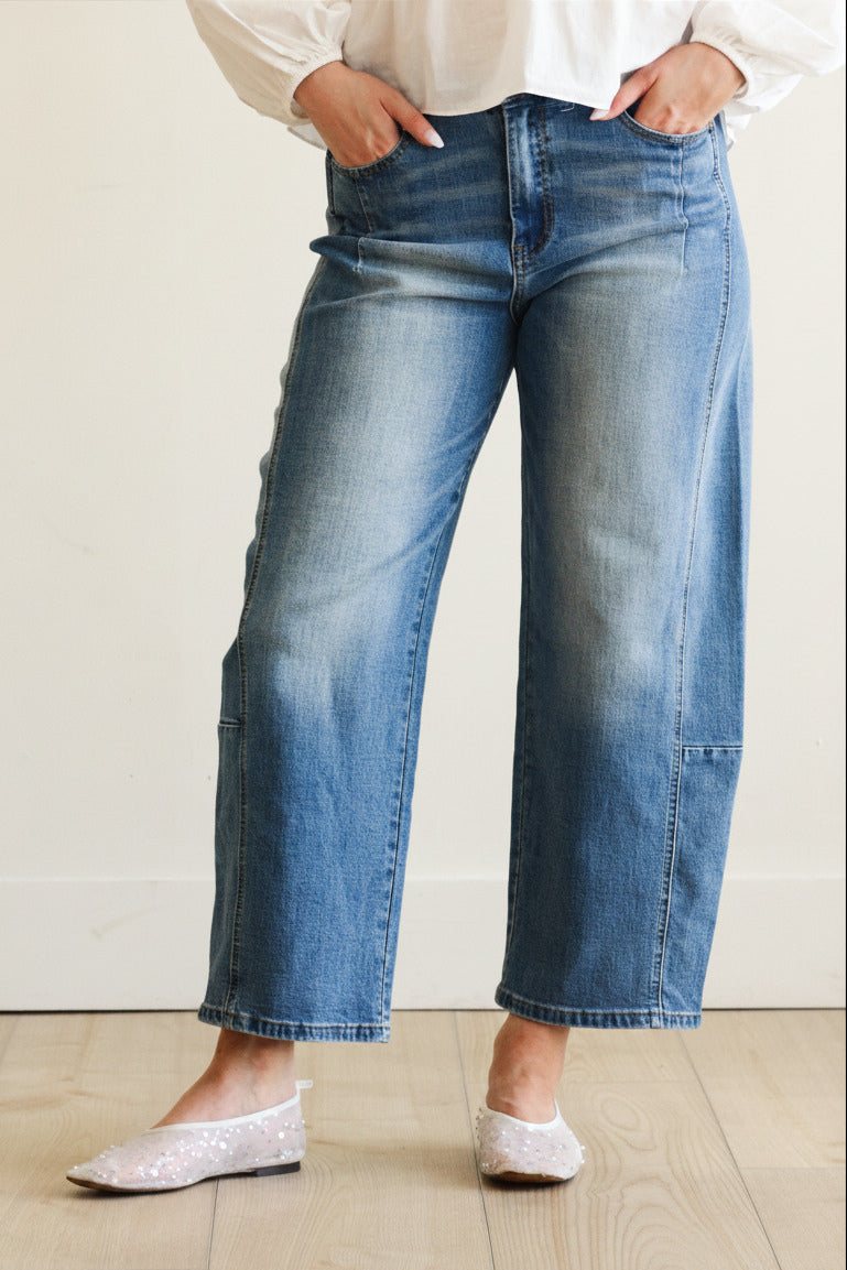 Person wearing blue jeans and white shoes on a plain background