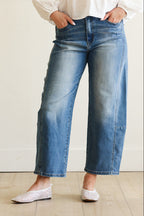 Person wearing blue jeans and white shoes on a plain background